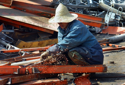 A worker cuts up scrap steel at a waste recycling factory in Nanjing, Jiangsu province. As a substitute for imported ore, recycled scrap metals currently accounts for 8 percent of total steel production in China.[China Daily]