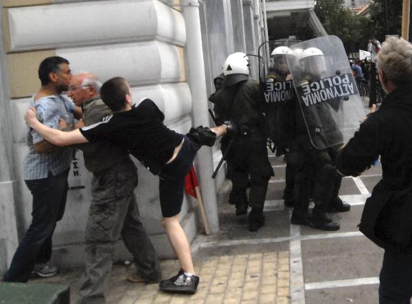Greek anarchists clash with riot police during a protest in downtown Athens, capital of Greece, May 5, 2010. Three people died in a fire that broke out at a bank and some 40 others injured on Wednesday during a massive protest against austerity measures which turned out to be a violence in downtown Athens. [Phasma/Xinhua]