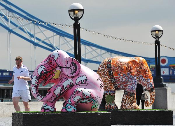 A jogger runs past painted elephant sculptures near Tower Bridge in London, capital of Britain, May 5, 2010. Over 250 brightly painted life-size elephants are located over central London. This is a conservation campaign that shines a multi-coloured spotlight on the urgent crisis faced by the endangered Asian elephant. The art works will be put into auction aiming to raise fund for the Asian elephants. [Xinhua/Zeng Yi]