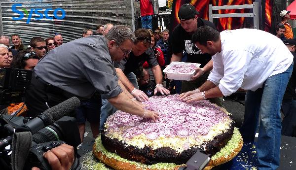 Barbecue chef and assistants add onion to a giant hamburger in Toronto, May 7, 2010. Barbecue chef Ted Reader and his assistants made a hamburger with a weight of 590 pounds (267.6 kilograms). The hamburger is waiting to be affirmed as a new Guinness World Record for world&apos;s heaviest hamburger. [Xinhua] 