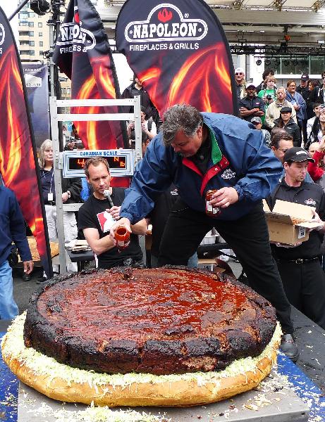 Barbecue chef Ted Reader (R front) adds sauce to a giant hamburger in Toronto, May 7, 2010. Barbecue chef Ted Reader and his assistants made a hamburger with a weight of 590 pounds (267.6 kilograms). The hamburger is waiting to be affirmed as a new Guinness World Record for world&apos;s heaviest hamburger. [Xinhua] 