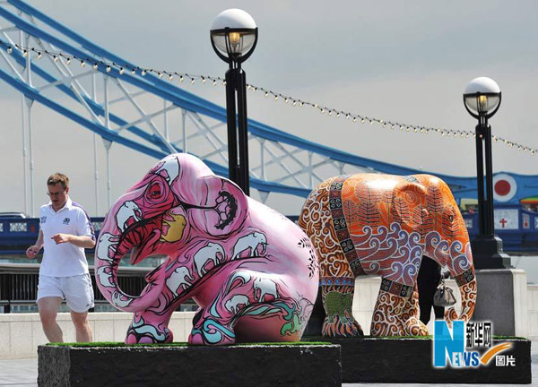 A man passes by a herd of life-sized &apos;baby elephants&apos; in London May 6, 2010. These highly collectable artworks will pop up at a host of London landmarks including Buckingham Palace, Parliament Square and the South Bank over the next few months, before being auctioned off. [Xinhua]