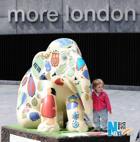 A baby takes a picture with an elephant sculpture in London May 6, 2010. A herd of life-sized &apos;baby elephants&apos; hand-painted by artists and designers were dotted around London to raise awareness of the plight of Asian elephants. [Xinhua]