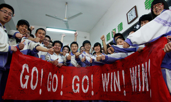 Students gesture after they sign their names on a banner to cheer up for the intensive preparation for the national college entrance examination at a high school in Jinan, East China's Shandong province, May 6, 2010.