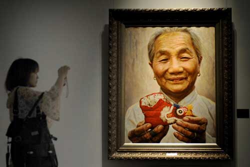 A visitor takes a photo of a painting by Li Zijian during an exhibition entitled 'Humanity and love”ahead of Mother's Day in Hunan Provincial Museum in Changsha, Central China's Hunan province, May 7, 2010.