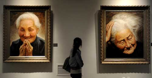 A woman looks at paintings by Li Zijian during an exhibition entitled 'Humanity and love” ahead of Mother's Day in Hunan Provincial Museum in Changsha, Central China's Hunan province, May 7, 2010.