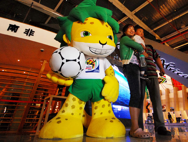 Tourist pose for photos with Zakumi, the mascot of 2010 World Cup of South Africa, in South Africa Pavilion at the 2010 World Expo in Shanghai, east China, on May 7, 2010. The decoration design of South Africa Pavilion and Brazil Pavilion at the 2010 World Expo are both in the theme of football as they will respectively host the 2010 World Cup of South Africa and 2014 World Cup of Brazil.