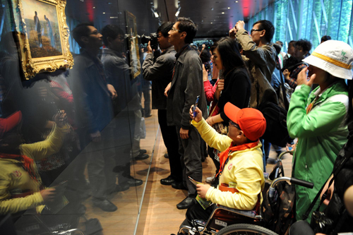 A disabled boy from a primary school of Dujiangyan city, Sichuan province, takes photos of a famous painting in France Pavilion at the Shanghai World Expo Site, May 8, 2010. [Xinhua]