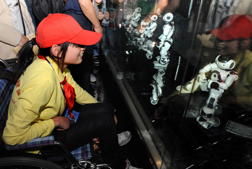 A disabled girl from a primary school of Dujiangyan city, Sichuan province, watches performance by intelligent robots in France Pavilion at the Shanghai World Expo Site, May 8, 2010. [Xinhua]