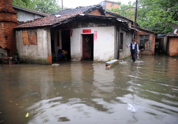 A man walks on a flooded street in Nanchang, capital of east China's Jiangxi Province, on May 8, 2010. Heavy rain hit Nanchang on Saturday and caused flood in the city. [Zhou Ke/Xinhua]
