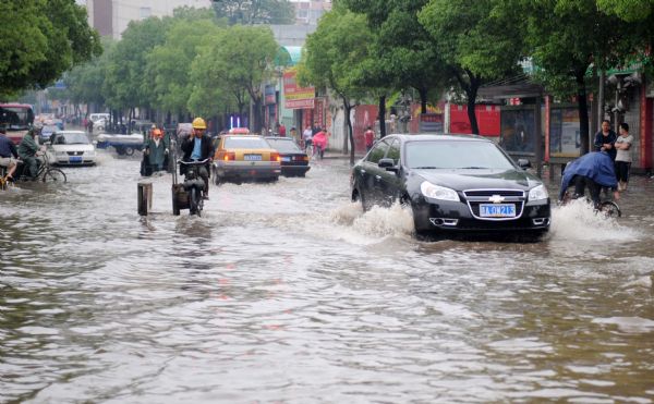 Vehicles run on a flooded street in Nanchang, capital of east China's Jiangxi Province, on May 8, 2010. Heavy rain hit Nanchang on Saturday and caused flood in the city. [Zhou Ke/Xinhua]