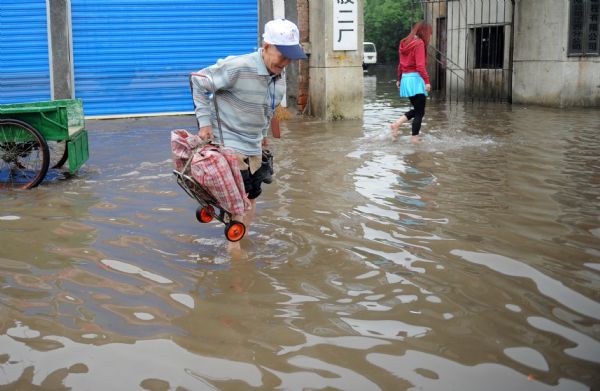 Citizens walk on a flooded street in Nanchang, capital of east China's Jiangxi Province, on May 8, 2010. Heavy rain hit Nanchang on Saturday and caused flood in the city. [Zhou Ke/Xinhua]