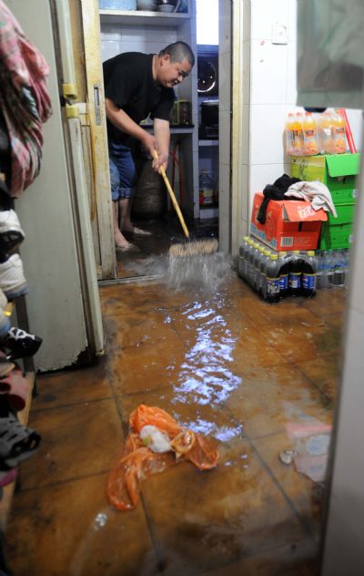 Shu Hui, a resident in Nanchang, sweeps water out of his room in Nanchang, capital of east China's Jiangxi Province, on May 8, 2010. Heavy rain hit Nanchang on Saturday and caused flood in the city. [Zhou Ke/Xinhua]