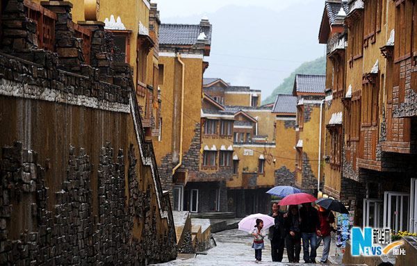 Several tourists walk in an ethnic building that features Jiang architectural flourishes on May 9, 2010. [Photo: Xinhua]