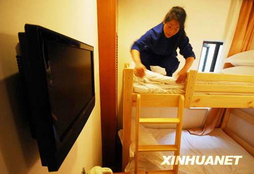 A staff member cleans a double room in a newly built mini hotel located in the center of Shanghai city, April 13, 2009. Taking up only about 7 square meters, the room comes complete with all necessary facilities, including a private bathroom. Each such room costs around 100 RMB (14.6 USD) per night. [File Photo: Xinhuanet] 