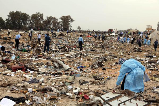 Rescue workers examine the debris of the crashed plane at the spot in Libyan capital of Tripoli, May 12, 2010. Afriqiyah Airways said in a statement there were 93 passengers and 11 crews aboard the plane, which crashed at Tripoli airport early Wednesday morning. [Xinhua photo]