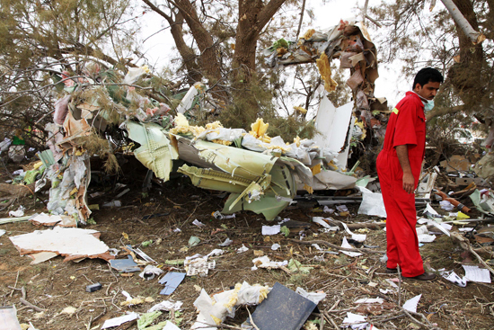 Rescue workers examine the debris of the crashed plane at the spot in Libyan capital of Tripoli, May 12, 2010. Afriqiyah Airways said in a statement there were 93 passengers and 11 crews aboard the plane, which crashed at Tripoli airport early Wednesday morning. [Xinhua photo]