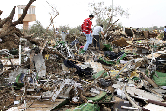 Rescue workers examine the debris of the crashed plane at the spot in Libyan capital of Tripoli, May 12, 2010. Afriqiyah Airways said in a statement there were 93 passengers and 11 crews aboard the plane, which crashed at Tripoli airport early Wednesday morning. [Xinhua photo]