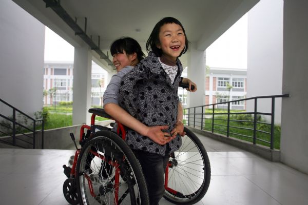 Gao Xiaoqin (L) from Xiaojin County and Li Yao from Beichuan County play at the wheelchair-accessible passage in You'ai School of Dujiangyan, Sichuan Province, on May 7, 2010. 