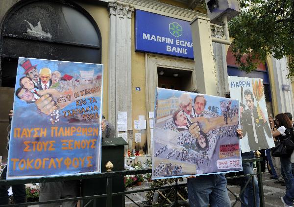 Greek protesters hold placards denouncing the EU-IMF supported austerity measures during a demonstration organized by labor unions in Athens, capital of Greece, May 12, 2010. The two umbrella labor unions of public and private sector employees ADEDY and GSEE called for a new general strike on May 20. [Phasma/Xinhua]