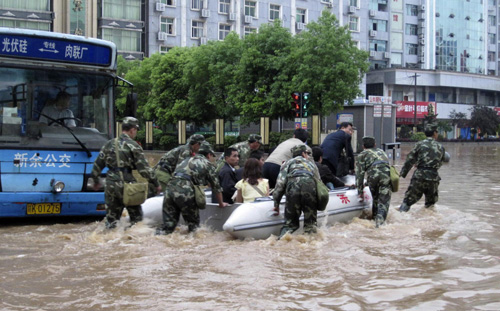 Soldiers transfer stranded passengers from a bus to safe places in Xinyu, East China's Jiangxi province on May 13, 2010. About 2,000 passengers were stranded at the Xinyu Railway Station on Thurday by floods which have been cause by heavy rains.