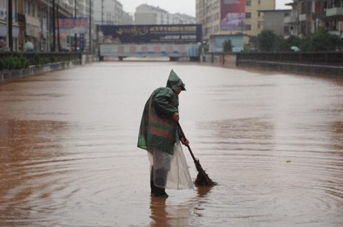 A worker works in a flooded street in Xinyu, East China's Jiangxi province on May 13, 2010.