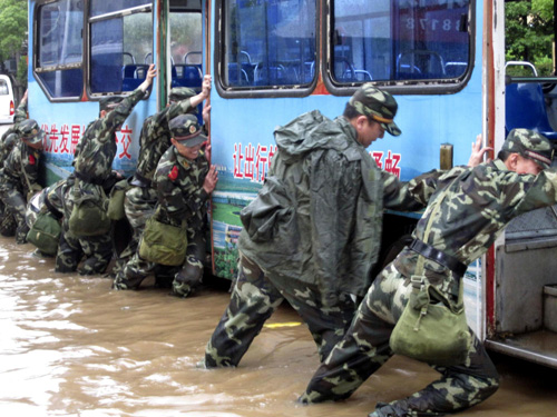 Soldiers push-start a bus in a flooded street in Xinyu, east China's Jiangxi province on May 13, 2010. 