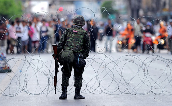 A Thai soldier sets a razor wire cordon after clashes with anti-government protesters in Bangkok on May 14, 2010. Thai troops opened fire on 'Red Shirt' protesters during clashes in the heart of Bangkok that left one person dead and at least 21 injured. 