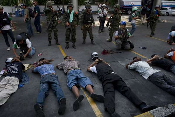 Thai soldiers (up) arrest ''Red shirt'' anti-government protesters (bottom) after they clashed in Bangkok on May 14, 2010. Thai troops opened fire on 'Red Shirt' protesters during clashes in the heart of Bangkok that left one person dead and at least 21 injured. 