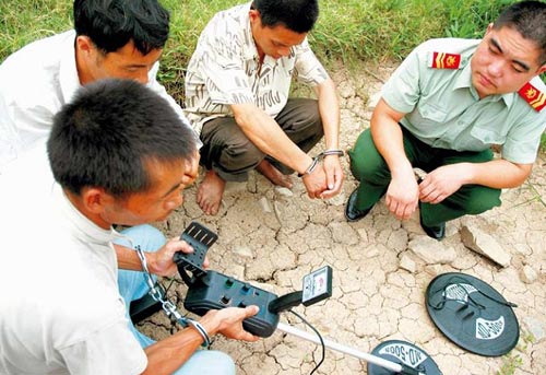 One of the three grave robbers who were caught by the police in southeast China&apos;s Zhejiang Province in 2007 is showing how to use a remote sensor.