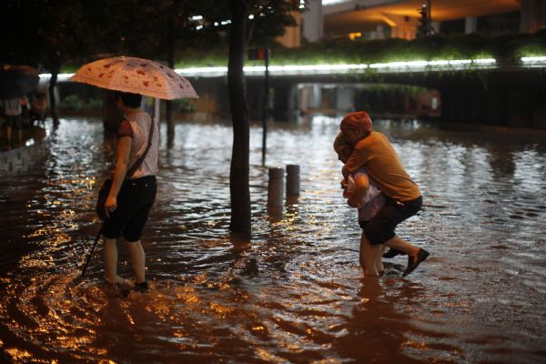 People walk in floods in Guangzhou, capital of south China's Guangdong Province, May 14, 2010. A rainstorm poured into Guangzhou Friday night, which flooded parts of the urban area in the city. 