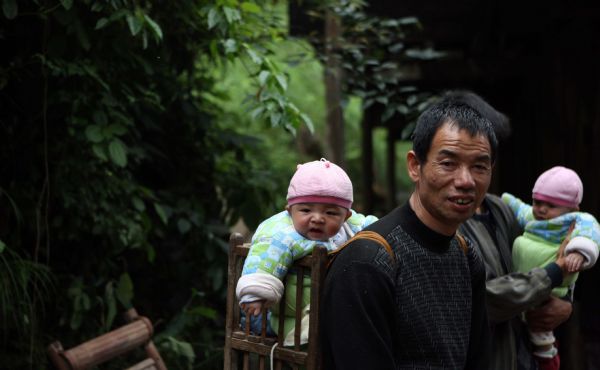 A villager and his twin grandsons are seen in a photo taken on May 16, 2010, in Zhuxi village of Xupu County in Huaihua City, central China&apos;s Hunan Province. Heavy rains triggered mountain torrents in Xupu County on Wednesday and Thursday, causing damage to its four major bridges and the trunk roads linking Shanxi Town to the outside.[Xinhua] 