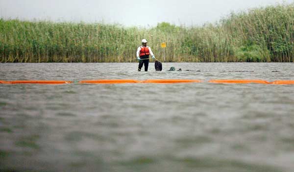 A cleaner is seen deploying an oil containment boom along the coast in Louisiana, May 11, 2010. So far, the emergency measures taken to contain the oil spill in the Gulf of Mexico have proven to have little effect. There are still about 5,000 barrels of oil leaking into the gulf. U.S. president Barack Obama called the oil spill a massive and potentially unprecedented environmental disaster. [163.com] 