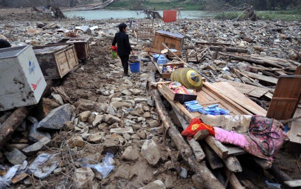 A villager walks past ruins to wash clothes after flash floods in Zhuxi village of Xupu County in Huaihua City, Hunan Province, May 16, 2010. Heavy rains triggered flash floods there on Wednesday and Thursday, causing damage to the major bridges and the trunk roads.