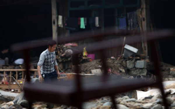 A resident searches in the rubbles after flash floods in Zhuxi village of Xupu County in Huaihua City, Hunan Province, May 16, 2010. Heavy rains triggered flash floods in Xupu County on Wednesday and Thursday, causing damage to its four major bridges and trunk roads.