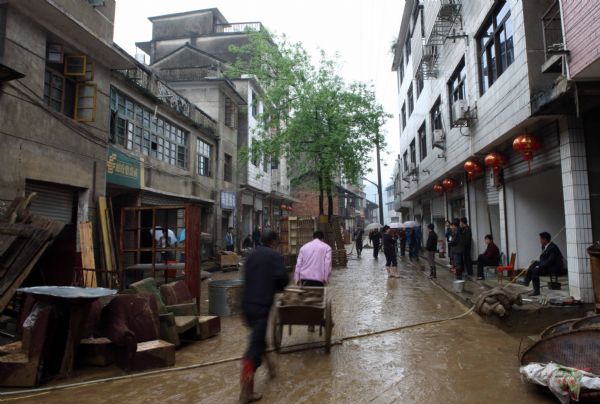 Residents carry silt in Shanxi Town of Xupu County in Huaihua City, Hunan Province, May 15, 2010. Heavy rains triggered flash floods in Xupu County on Wednesday and Thursday, causing damage to its major bridges and trunk roads. 