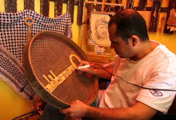 Palestinian sculpture artist Nasser Flefel, 39, decorates a wooden key with the names of villages which were occupied during the war with Israel in 1948 in his wood-carving shop in Gaza city, May 16, 2010. 