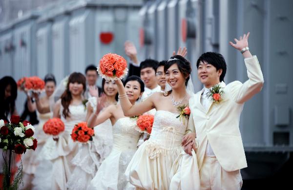 Newlyweds wave to friends and relatives at the group wedding at the factory of Shenyang Transformer Group Co.,Ltd of Tebian Electric Apparatus Stock Co.,Ltd (TBEA) in Shenyang, capital of Liaoning Province, May 16, 2010. Thirty pairs of newlyweds held a group wedding in the factory where they work on Sunday. 