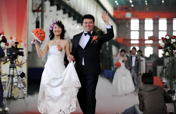 Newlyweds wave to friends and relatives at the group wedding at the factory of Shenyang Transformer Group Co.,Ltd of Tebian Electric Apparatus Stock Co.,Ltd (TBEA) in Shenyang, capital of Liaoning Province, May 16, 2010. Thirty pairs of newlyweds held a group wedding in the factory where they work on Sunday. 