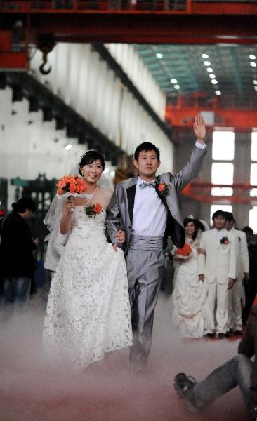 Newlyweds wave to friends and relatives at the group wedding at the factory of Shenyang Transformer Group Co.,Ltd of Tebian Electric Apparatus Stock Co.,Ltd (TBEA) in Shenyang, capital of Liaoning Province, May 16, 2010. Thirty pairs of newlyweds held a group wedding in the factory where they work on Sunday.