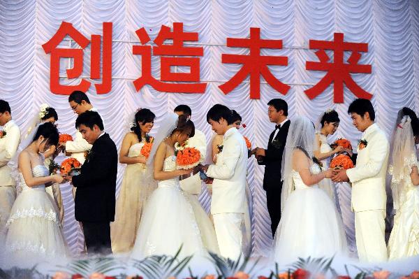 Newlyweds exchange rings at the group wedding at the factory of Shenyang Transformer Group Co.,Ltd of Tebian Electric Apparatus Stock Co.,Ltd (TBEA) in Shenyang, capital of Liaoning Province, May 16, 2010. Thirty pairs of newlyweds held a group wedding in the factory where they work on Sunday. 