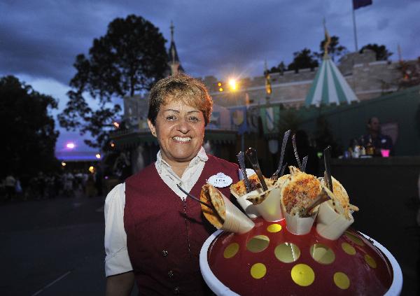 A staff member presents food at Disney's Magic Kingdom Park during a welcome event prior to the 2010 International POW WOW in Orlando, Florida, the United States, May 16, 2010. The annual premier international marketplace for travel to the United States, will gather over 1,000 U.S. travel organizations and worldwide tourism operators. [Xinhua/Zhang Jun]