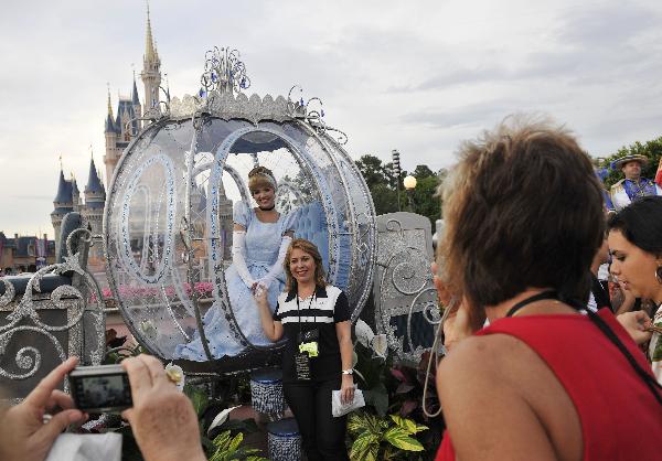  A woman poses for a photo with Cinderalla at Disney's Magic Kingdom Park, during a welcome event prior to the 2010 International POW WOW in Orlando, Florida, the United States, May 16, 2010. The annual premier international marketplace for travel to the United States, will gather over 1,000 U.S. travel organizations and worldwide tourism operators. [Xinhua/Zhang Jun]