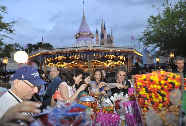 People try candies at Disney's Magic Kingdom Park, during a welcome event prior to the 2010 International POW WOW in Orlando, Florida, the United States, May 16, 2010. The annual premier international marketplace for travel to the United States, will gather over 1,000 U.S. travel organizations and worldwide tourism operators. [Xinhua/Zhang Jun]