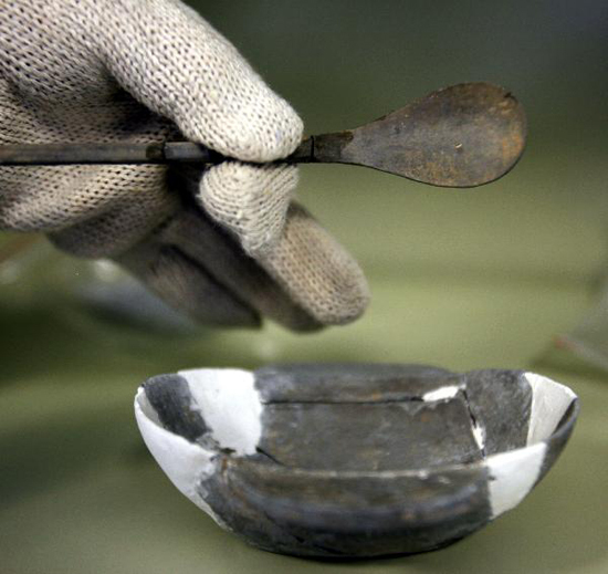 Photo taken on May 14, 2010 shows a bowl and a bronze spoon unearthed at the excavation site of the tomb of Cao Xiu, a noted general from the Three Kingdoms period (220-280 A.D.) in Mangshan of Luoyang City, central China's Henan Province. Archeologists of Henan provincial cultural heritage bureau confirmed that they have founded the tomb of Cao Xiu during the tomb excavation in Mengjin County of Luoyang City at a press conference on Monday. [Xinhua photo]