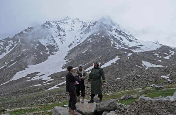 Afghan officials and policemen stand near the mountains where an Afghan Pamir Airways plane is believed to have crashed in the Salang pass, north of Kabul. 