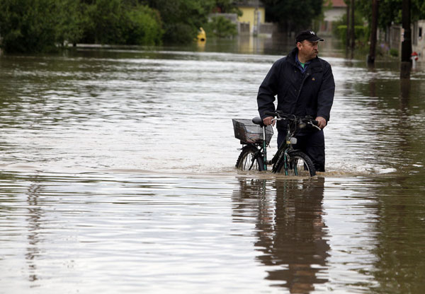 A local man pushes his bicycle in the flooded Vadasz stream in Szikszo in north-east Hungary, about 200 kms from Budapest on May 17, 2010 as heavy rainfall and floods hit Hungary at the weekend.