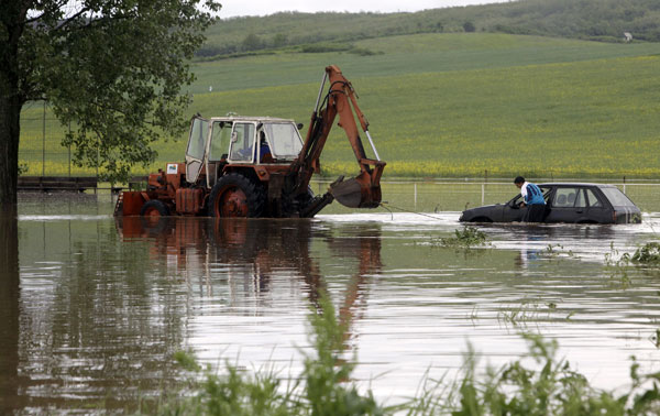 A car is salvaged by a tractor in the flood waters of Vadasz stream near Alsovadasz village on May 17, 2010 as heavy rainfall and floods hit Hungary at the weekend.