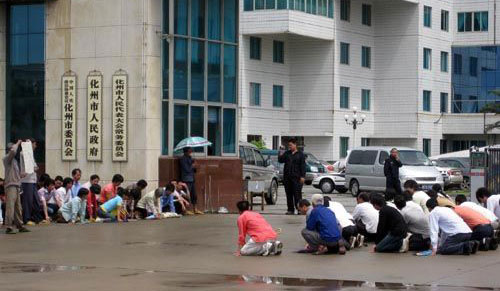 Villagers stay on their knees outside the city government building in Huazhou, South China's Guangdong province. [China.com]