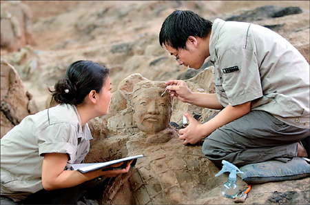 Archeologists examine terracotta figures newly excavated from the No 1 Pit of the Terracotta Museum in Lintong, Xi'an, in this picture taken in August last year and was released Tuesday, May 18, 2010. The museum said on Tuesday it had completed the latest round of excavation and restoration after a year's work. About 120 more figures, some of them painted in pink, red and lilac, were excavated. [China Daily]